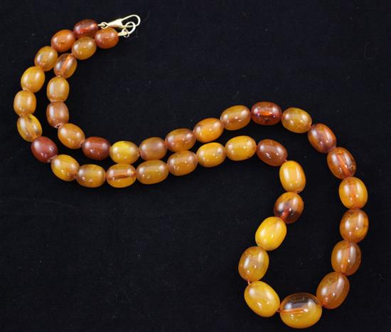 A single strand graduated oval amber bead necklace, 23in,